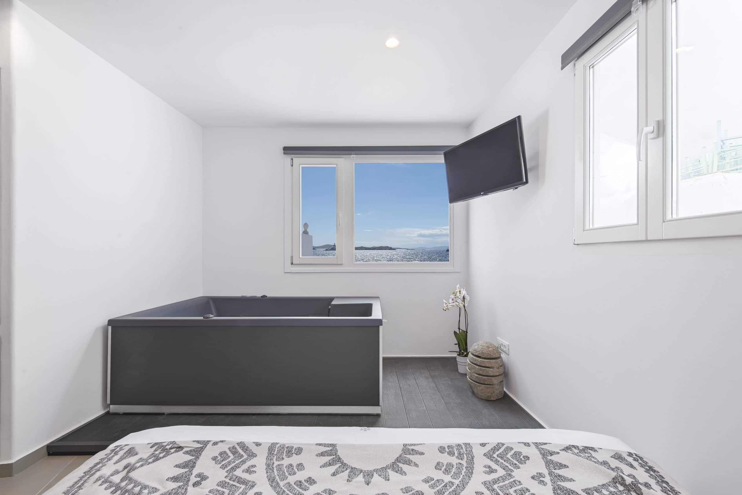 Indoor hot tub beneath a window looking out to the Aegean Sea